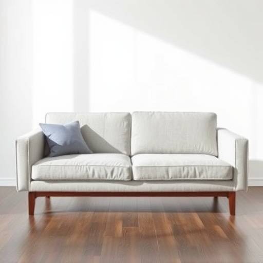 A modern, minimalist sofa upholstered in light gray fabric with dark wooden legs.